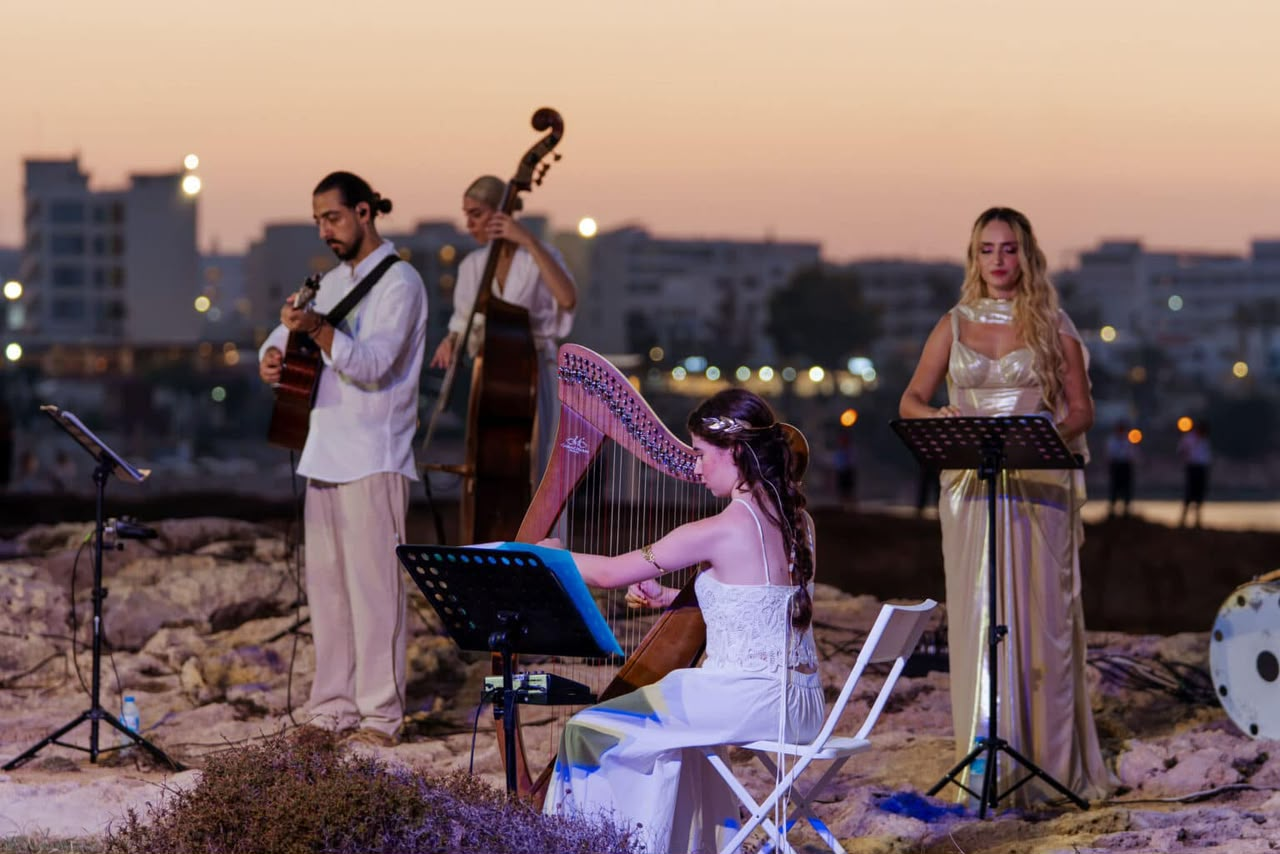 Angelina and the ensemble performing at sunset with the city skyline behind